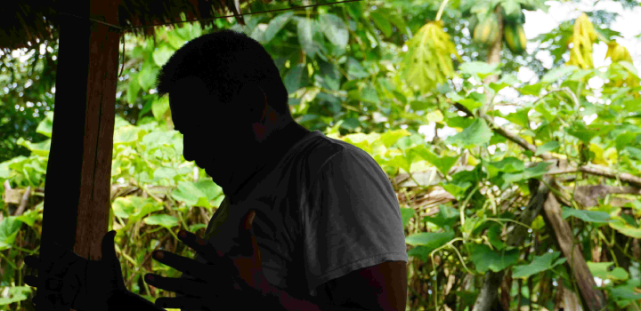 A foto mostra um homem orando e ao fundo uma paisagem verde, de floresta.